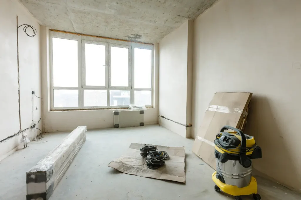 Empty room with a vacuum and materials stored neatly for job site equipment storage